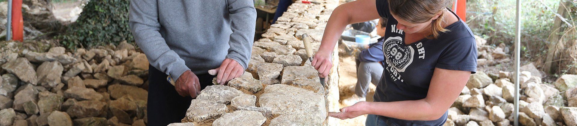 Plan de 2 bénévoles en train de restaurer un mur de pierre