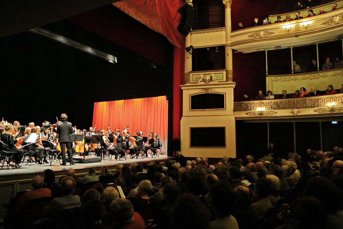 Plan large d'un concert de l'ONPL dans un théâtre à Saumur, vue sur la scène avec le public de dos