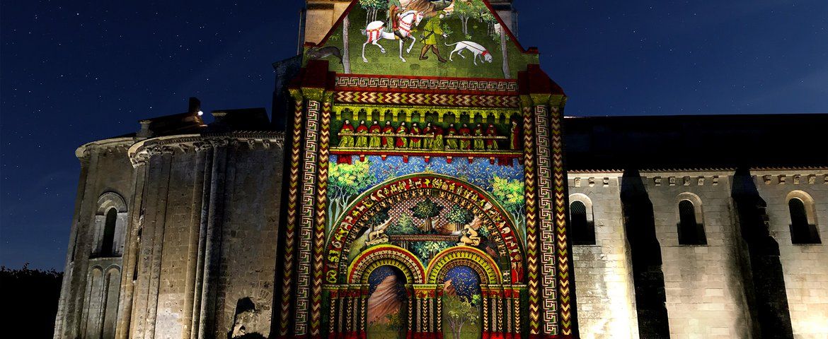 Vue du parvis d'une église illuminée par des dessins colorés projetés sur la façade
