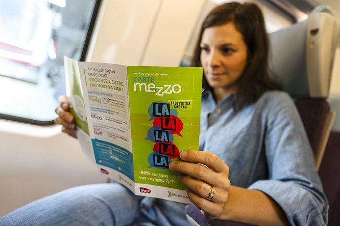 jeune femme dans le train lisant la plaquette de la carte mezzo