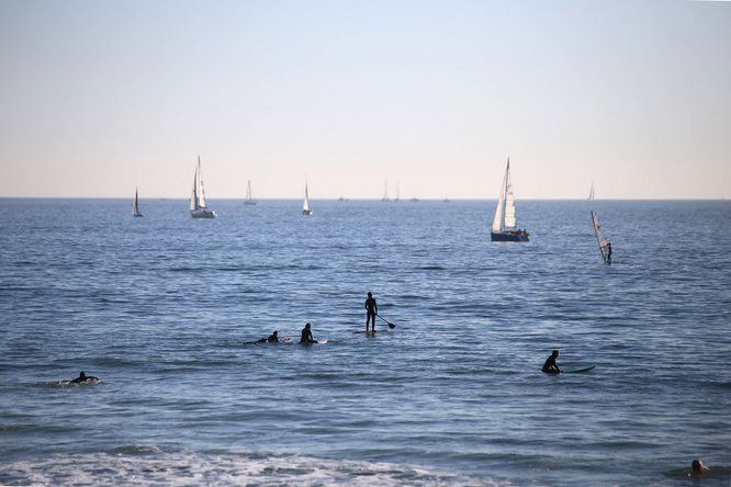 mer avec voiliers, paddle, surfeurs, baigneurs