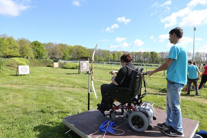 Personne en fauteuil roulant faisant du tir à l'arc en extérieur