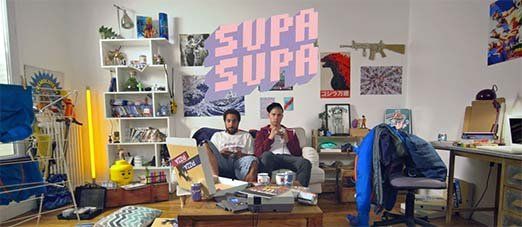 2 hommes dans un canapé jouent aux jeux vidéo dans un appartement à la décoration juvénile, extrait de la websérie supa supa