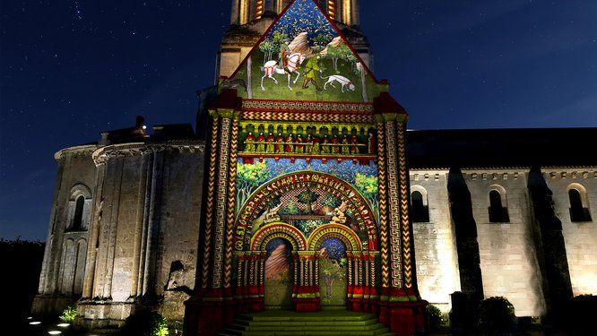 Vue du parvis d'une église illuminée par des dessins colorés projetés sur la façade
