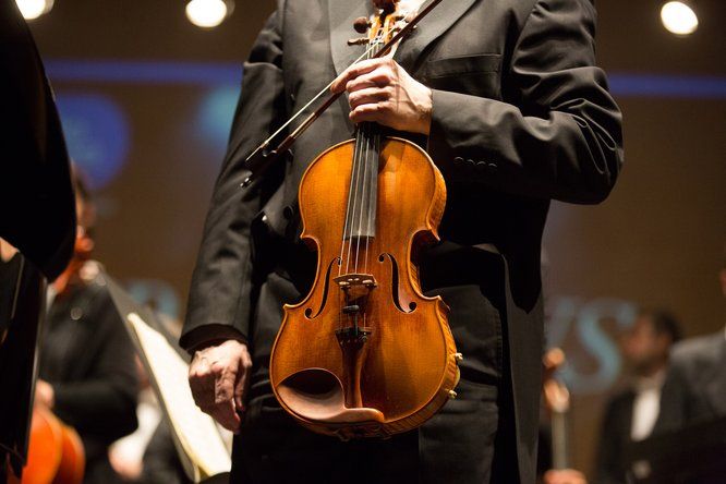 Gros plan sur un violon tenu par la main par un musicien 