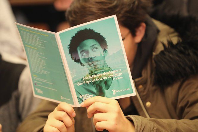 un lycéen lit une brochure au sujet du prix littéraire lycéens