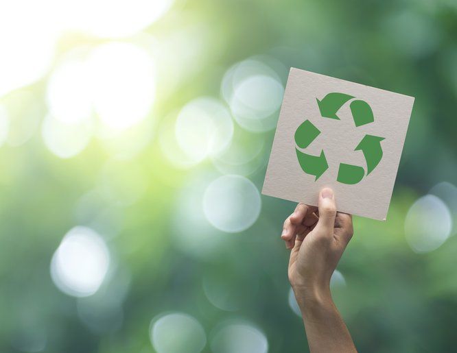 main tenant un papier avec le dessin du symbole du recyclage circulaire - voir version agrandie