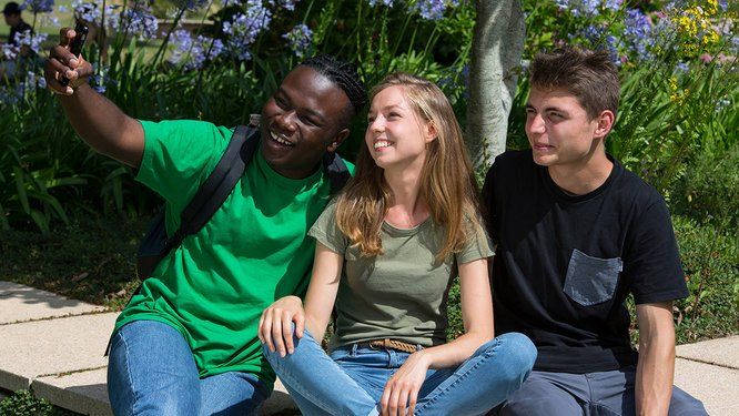 trois jeunes lycéens en train de se prendre en photo avec un smartphone