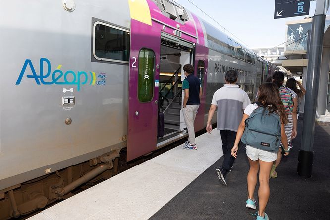 personnes marchant sur un quai et rentrant dans un train Aléop