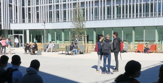 Vue d'une cour de lycée avec des groupes de lycéens masqués