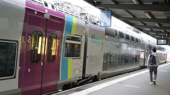 un homme de dos sur le quai de gare devant un TER