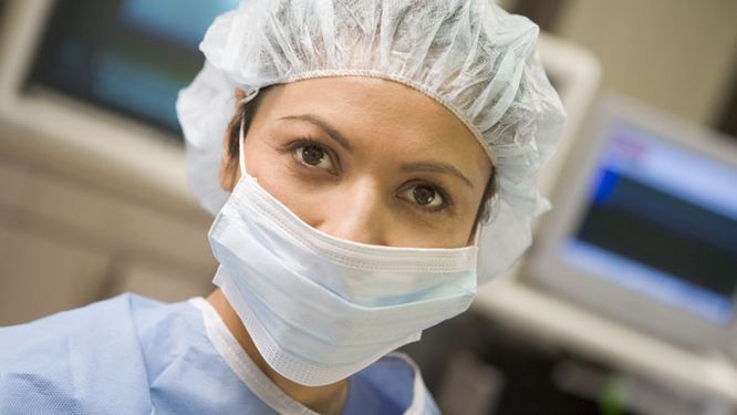 portrait de face d'une infirmière avec un masque et une charlotte