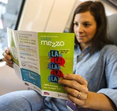 jeune femme dans le train lisant la plaquette de la carte mezzo