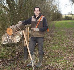Homme dans la campagne, bottes en caoutchouc et gilet de chasseur, outils forestiers