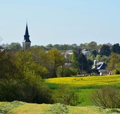 des champs et au loin un bourg avec un clocher et quelques habitations