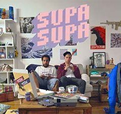 2 hommes dans un canapé jouent aux jeux vidéo dans un appartement à la décoration juvénile, extrait de la websérie supa supa
