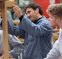 2 jeunes en formation apprennent à construire un objet avec l'aide d'un professeur 