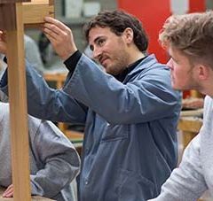 2 jeunes en formation apprennent à construire un objet avec l'aide d'un professeur