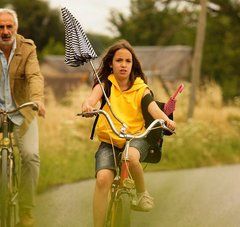 image du film : une petite fille et un homme à vélo sur une route de campagne